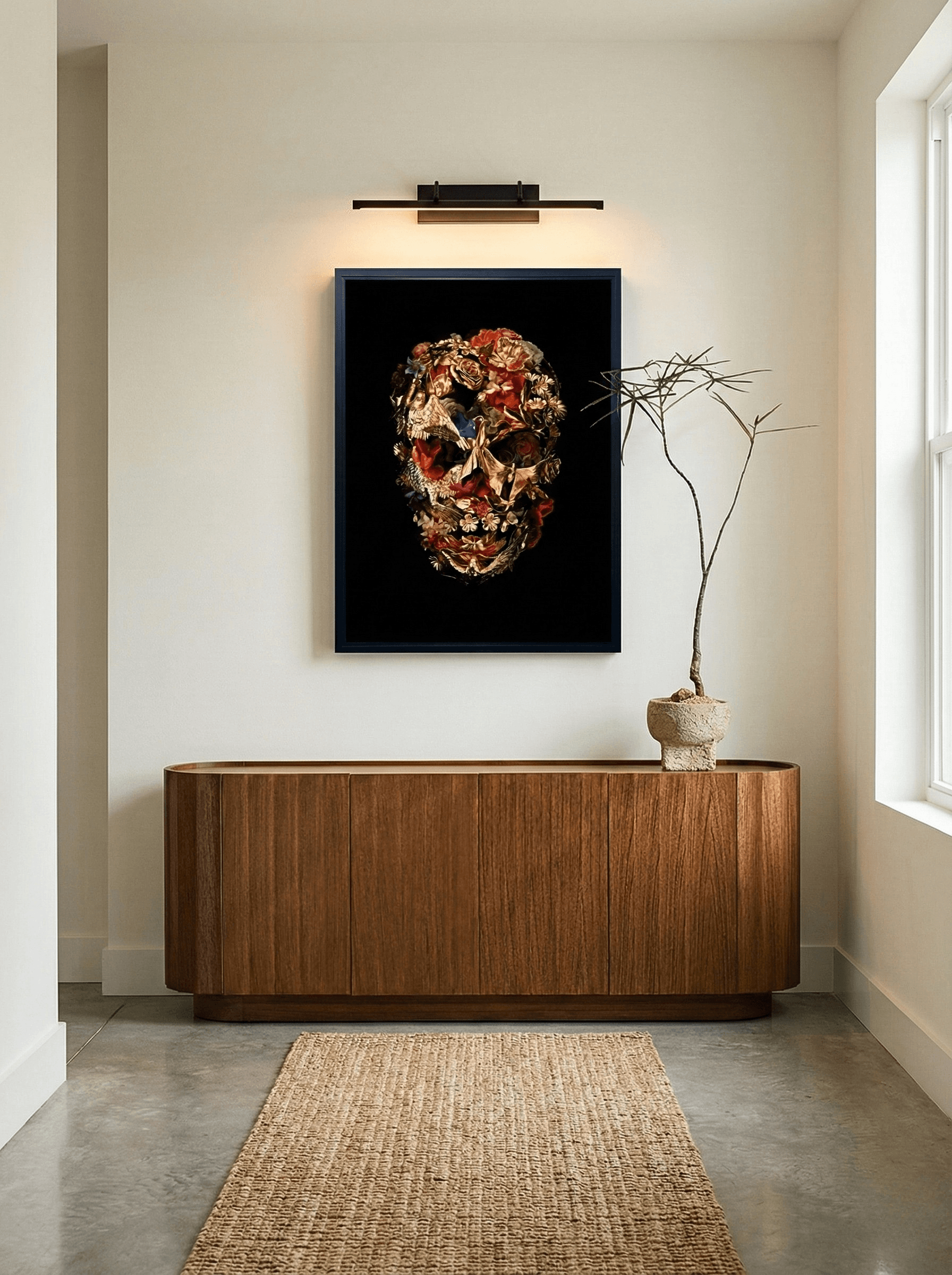 Framed gold and floral skull artwork above a wooden sideboard in a minimalist hallway.