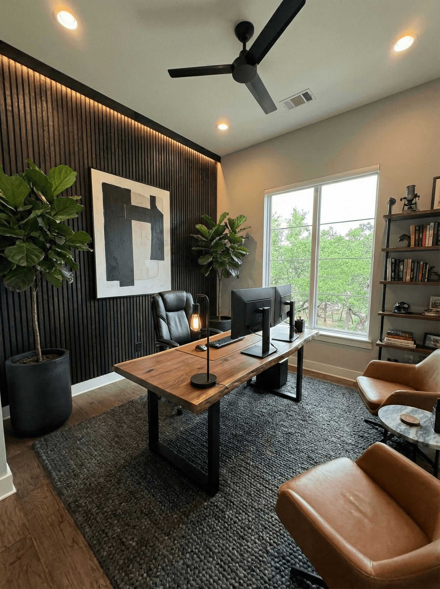 Modern home office with live edge desk, dark slat wall, and large fiddle leaf figs.
