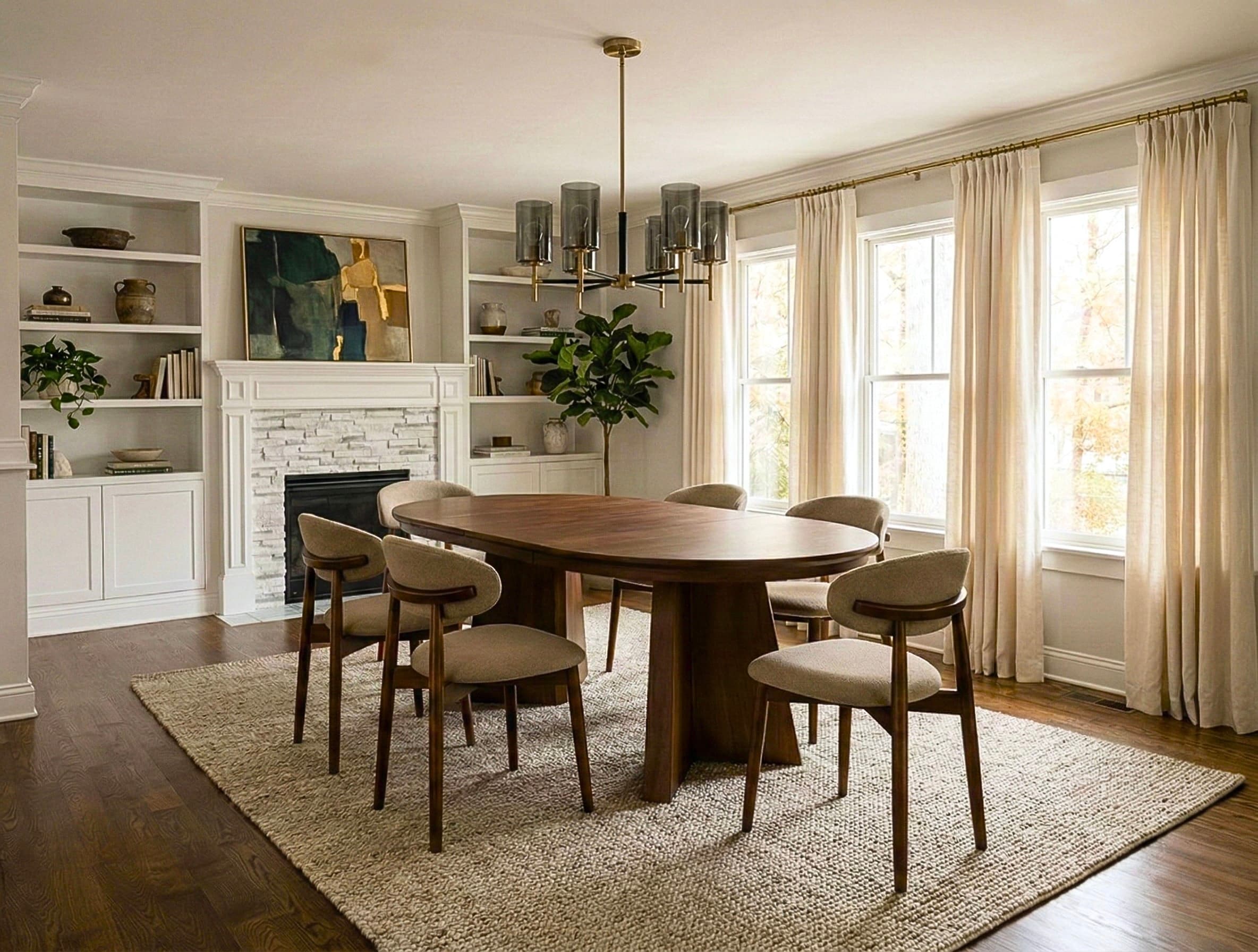 Modern dining room featuring an oval wood table, mid-century chairs, fireplace, and large windows.