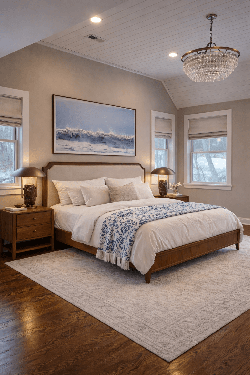 Serene bedroom featuring a wooden bed, ocean wave artwork, and a sparkling crystal chandelier.